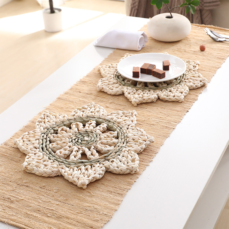 Handwoven corn husk flower-shaped placemat, empty, on a linen table runner