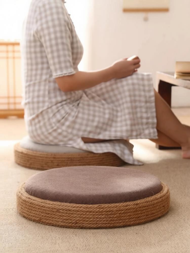 Japanese-style round tatami floor cushions with jute rope woven edge and soft grey linen fabric top, displayed in a minimalist Zen tea room setting